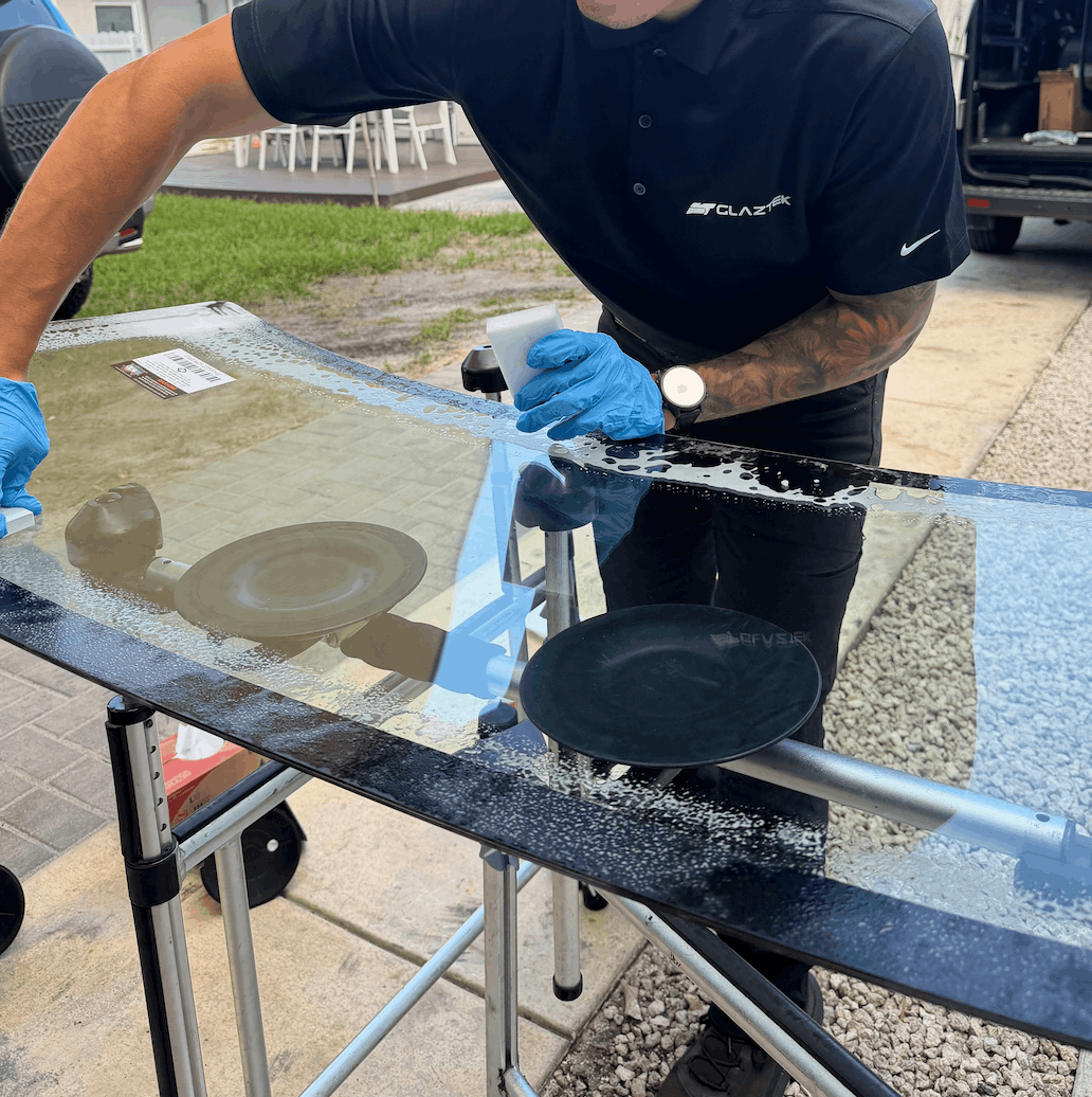 Técnico preparando un parabrisas nuevo antes de la instalación